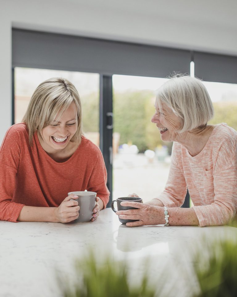 Mother and daughter laughing with coffee cups